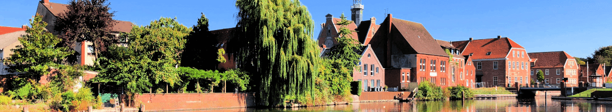 Rote Häuser und Bäume am Kanal- Ufer