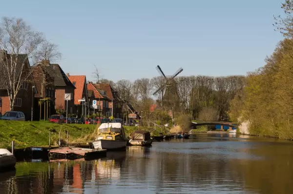 Boote auf Kanal in Emden Boote auf Kanal entlang Backsteinsiedlung mit Windmühle im Hintergrund