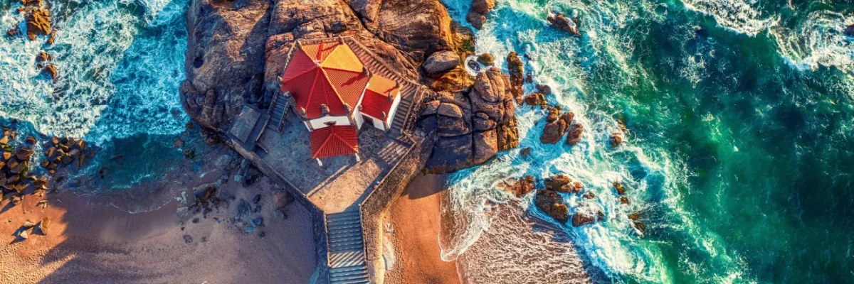 Luftbild zeigt die Capela do Senhor da Pedra, eine historische Kapelle aus dem 17. Jahrhundert. Die Kirche steht am Strand von  Vila Nova de Gaia, Portugal, das auf der anderen Seite des Douro liegt. Direkt neben Porto.
