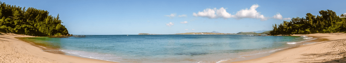 Blaues Meer im Zentrum des Bildes. Links und rechts sind der Strand und Palen zu sehen.