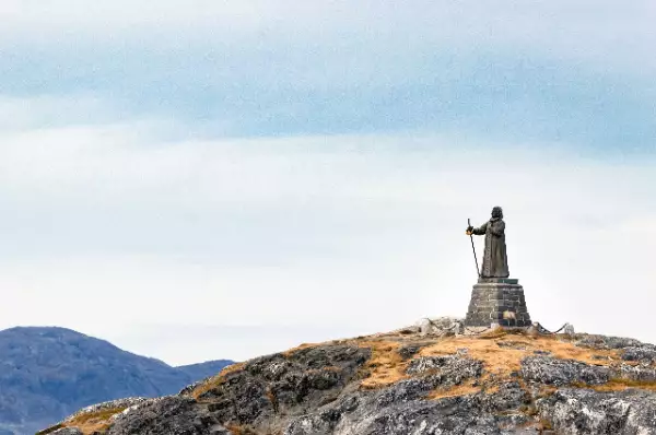 Statue Hans Egede Die Statue von Hand Egede steht auf einer Erhöhung und blickt in Richtung Abgrund. Man sieht hinter der Statue die Umrisse weiterer Felsen