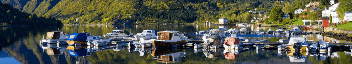 Auf einem See vor Ulvik liegen kleine Boote, welche sich im Wasser zusätzlich spiegeln