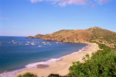Ein Strand auf der Isla Margarita mit Bergen im Hintergrund und klarem Himmel.