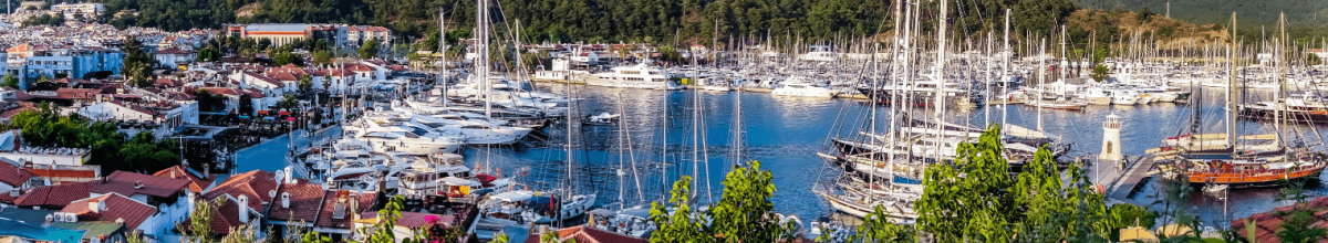 Panoramabild des Yachthafens von Marmaris in der Türkei mit Segelbooten und der Altstadt im Hintergrund.