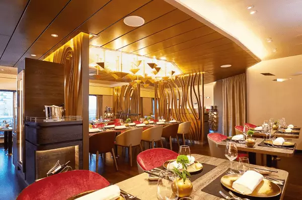 Restaurants auf der HANSEATIC inspiration Zu sehen ist die Bar und davor zwei Tische für jeweils vier Personen.
