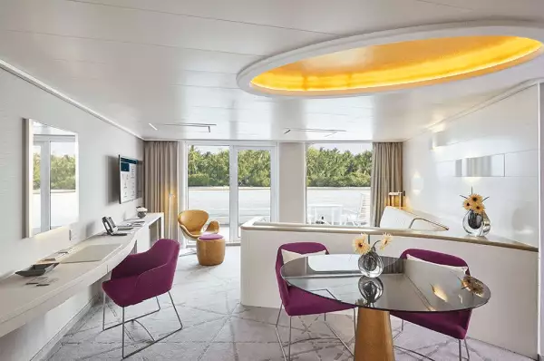 Suiten auf der HANSEATIC inspiration Zu sehen ist der abgetrennte Wohnbereich. Die Farbe sind beige gehalten mit lilanen Accessoirs.