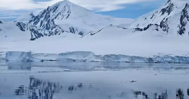 Die Hanseatic nature fährt in Richtung eines Eusberges. Dieser spiegelt sich im Wasser des Meers.