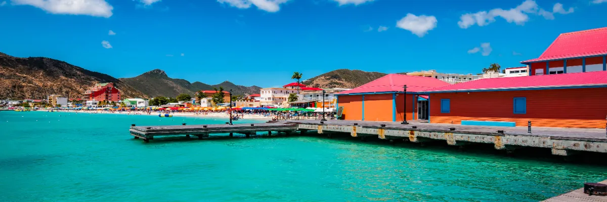 Bunte Häuser umranden eine kleine Hafenanlage in der Karibik mit wunderschönem, türkisem Wasser.