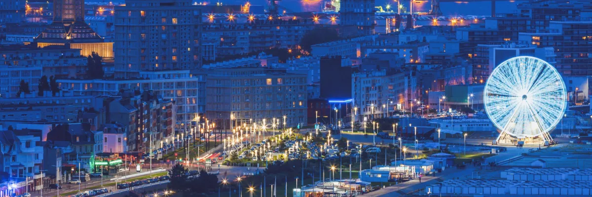 Die hell-beleuchtete Kulisse der Stadt Le Havre mit einem voll-illuminierten Riesenrad.