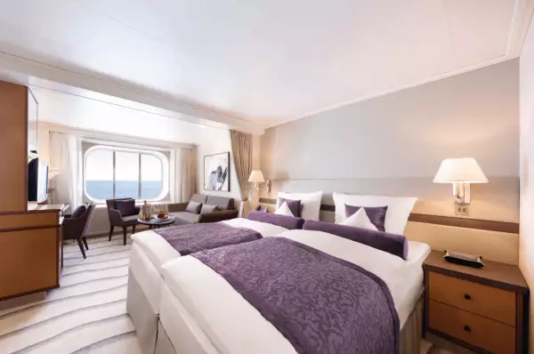 im Zentrum der Suit stehen zwei Betten. Diese sind in den Farben Weiß und Lila gehalten. Des Weiteren ist eine luxuriöse Ausstattung zu sehen.