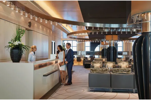 Erstklassiger Service und persönliche Betreuung an Bord von Hapag-Lloyd Cruises Rezeption an Bord eines Hapag-Lloyd Cruises Luxusschiffs: Elegantes Paar wird vom Crew-Mitglied begrüßt.