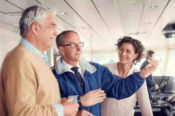 Service an Bord Ein Mann spricht mit einem Pärchen und unterstützt Sie auf ihrer Reise.