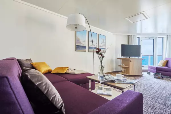 Premiumsuite mit lilafarbener Couch, TV und Balkon
