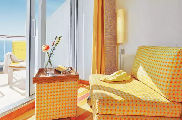 Balkonkabine in bordeauxroter Optik mit Doppelbett, Stuhl und Balkon