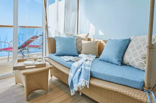 Junior- Suite mit Couch und Balkon im Hintergrund plus Liegestühlen