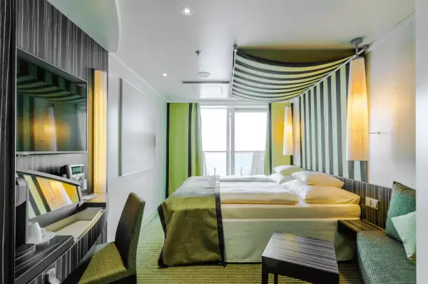 Panoramakabine in grüner Optik mit Doppelbett, Tisch und Stuhl und Balkon