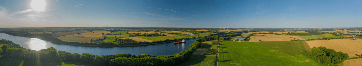 Nord-Ostsee-Kanal umgeben von Grünflächen, blauer Himmel und Sonnenschein