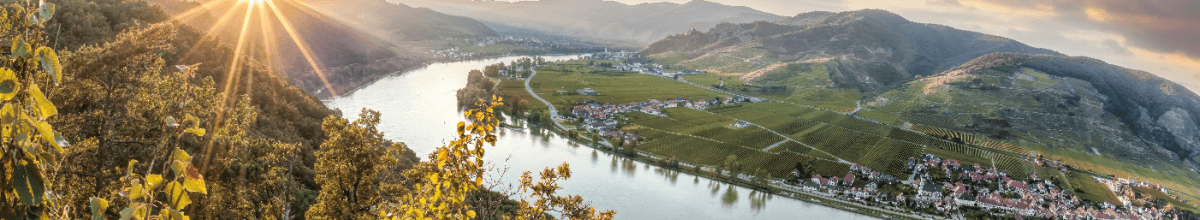 Panoramablick auf die Donau, die bei Sonnenschein durch ein Tal fließt.