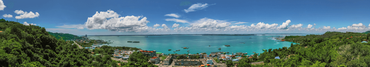 Sandakan- Luftaufnahme, Häuser, Meer im Hintergrund, rechts und links Bäume
