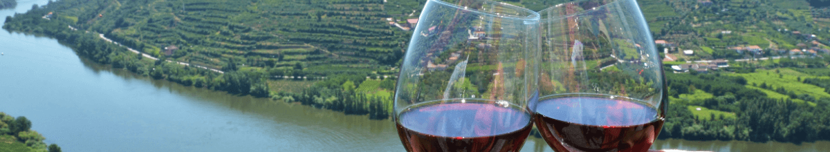 Mit Ausblick auf den Douro und das Douro-Tal werden zwei Rotweingläser angestoßen.
