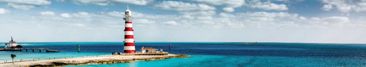 Das Ocean Cay MSC Marine Reserve empfängt Gäste mit strahlendem Sonnenschein und kristallklarem Wasser im Herzen der Karibik Panoramaaufnahme des rot-weiß gestreiften Leuchtturms auf Ocean Cay MSC Marine Reserve vor türkisblauem Wasser auf den Bahamas.