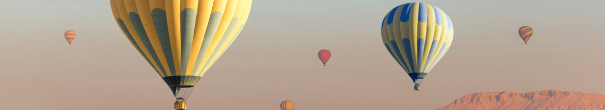 Zu sehen sind Heißluftballons wie sie in den Himmel steigen.