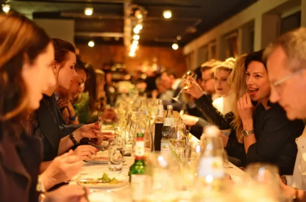 Personen sitzen an einer großen Tafel und genießen das 5-Gänge Menü von Sterneköchen auf der nickoSpirit von nicko cruises.