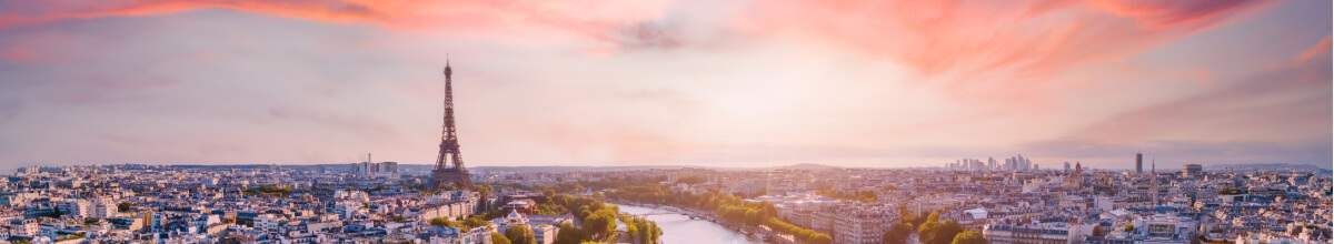 Zu sehen ist der romantische Himmel von Frankreich. Im Hintergrund sieht man den Eifelturm zwischen den Häusern und Gebäuden herausstechen.