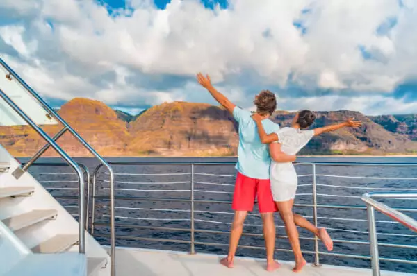 Paar von hinten auf Kreuzfahrtschiff mit Blick auf das Meer