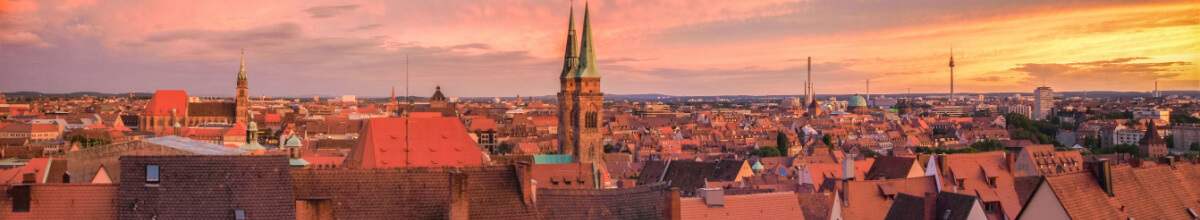 Dächer von Nürnberg bei Sonnenuntergang mit Kirche im Zentrum.