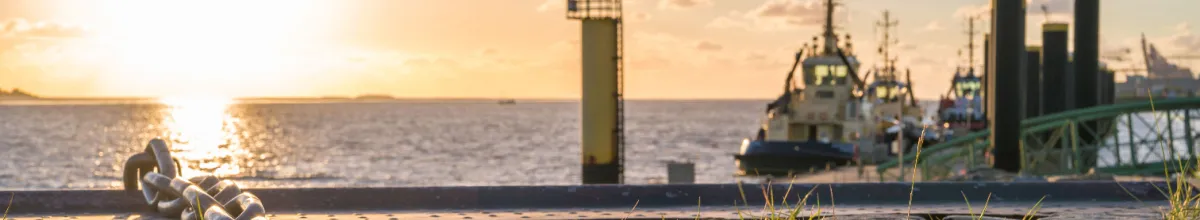 Ausblick auf einen Anleger in Bremerhaven bei Sonnenuntergang mit einem Schiff vor Anker.