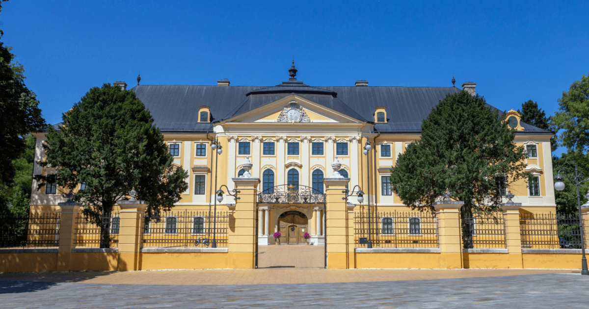 Kalocsa: Erzpalast davor Bäume und ein Zaun