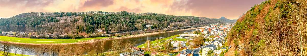 Bei romatischer Atmosphäre erstahlt Bad Schandau. Zu sehen ist die Elbe, sowie ein Felsvorsprung und die Stadt.