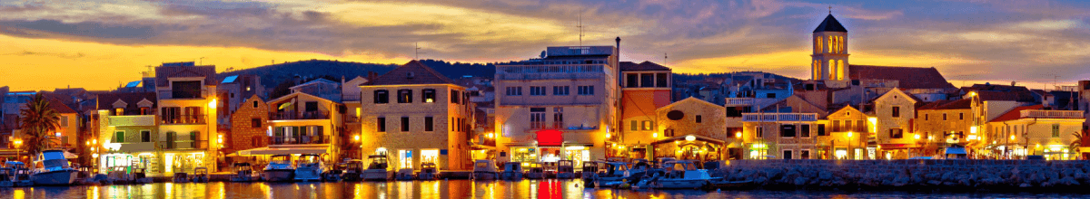 Panoramablick auf Vodice, bei Sonnenuntergang mit erleuchtetem Hafen.