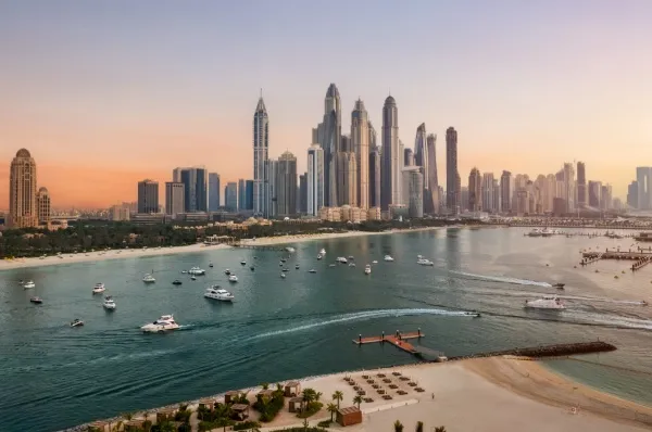Dubai Marina Skyline bei Sonnenuntergang mit Booten und Yachten im Vordergrund.