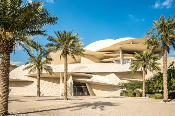 Modernes weißes Gebäude mit interessanter Architektur von Palmen umgeben.