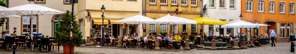 Viele Menschen sitzen in der Altstadt vor den Geschäften und Restaurants.