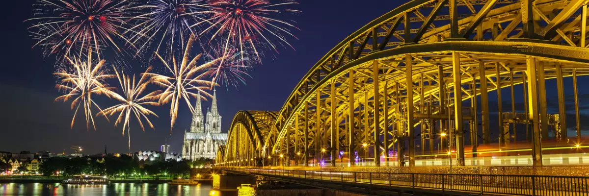 Buntes Feuerwerk über Köln. Kölner Dom und die beleuchtete Hohenzollernbrücke am Abend.