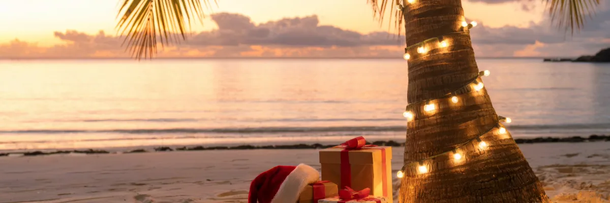 Geschenke unter einer Palme auf dem Strand – Symbol von Festtagen.