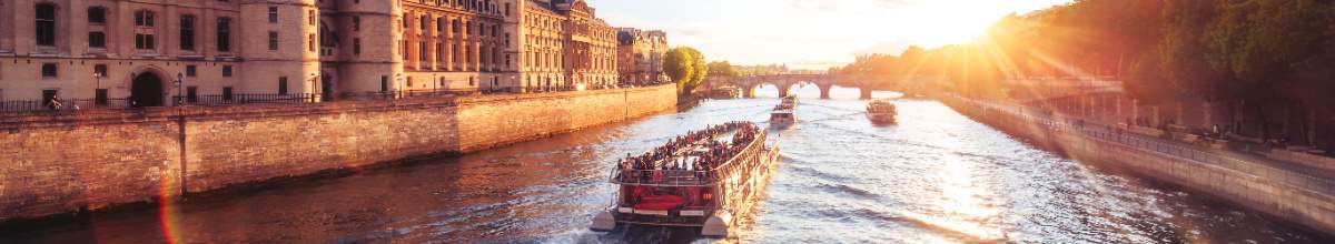 Das Kreuzfahrtschiff fährt der Sonne entgegen auf der Seine.