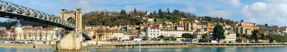 Links im Bild verläuft eine Brücke. Zentral verläuft die Saône. Im Hintergrund liegt die Stadt.