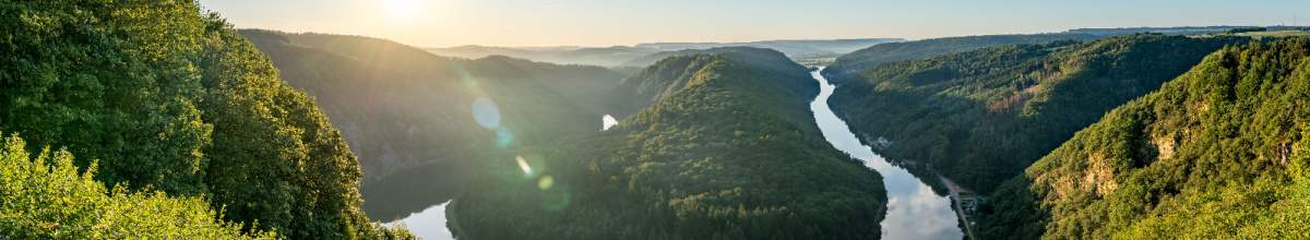 Die Sonne strahlt ins Auge des Betrachters. Sie küsst die Saar und die besondere Natur um die Saarschleife herum.